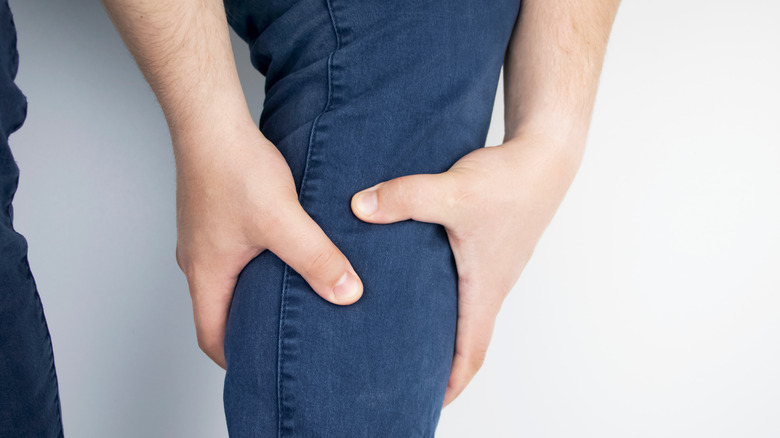 Person wearing jeans holding their calf