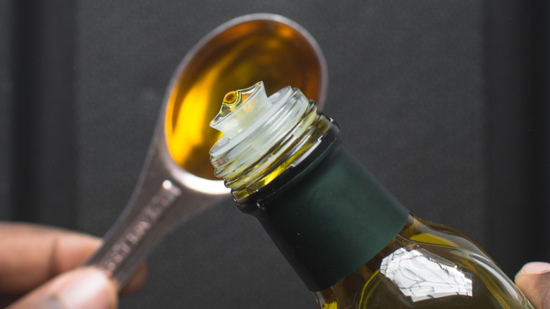 Person pouring a tablespoon of olive oil