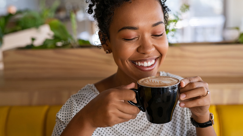 Woman drinking coffee with milk foam