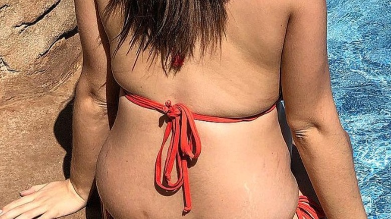 Stacey Solomon shows stretch marks on her back while at a pool