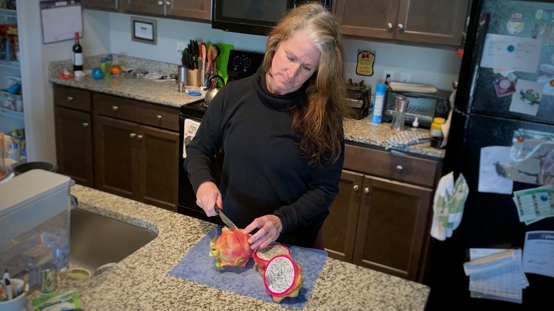 woman cutting red dragon fruit
