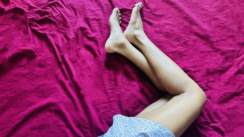Woman's legs on fuchsia bedsheet