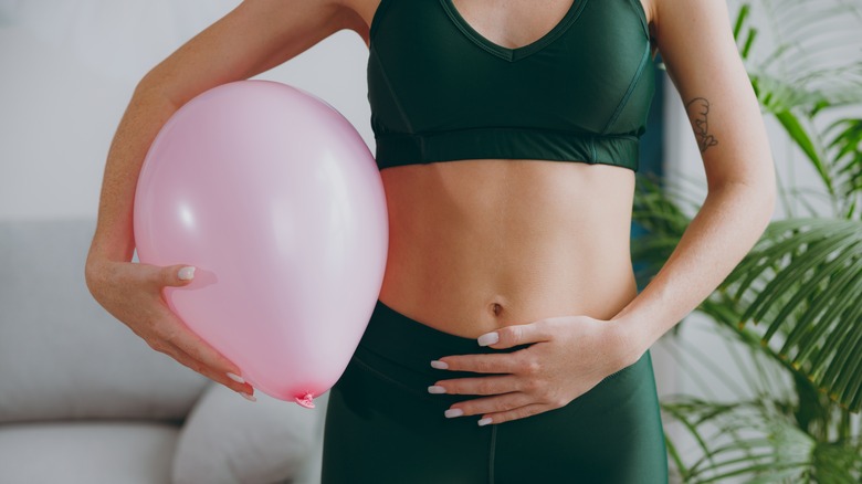 Woman with balloon holding her abdomen