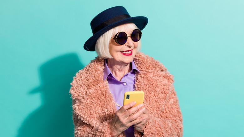 stylish older woman wearing a blue hat and textured pink jacket 