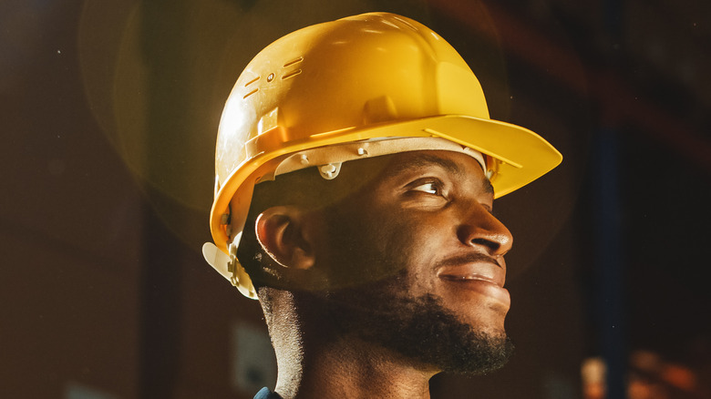 side profile of a construction worker wearing a hat and reflective vest 