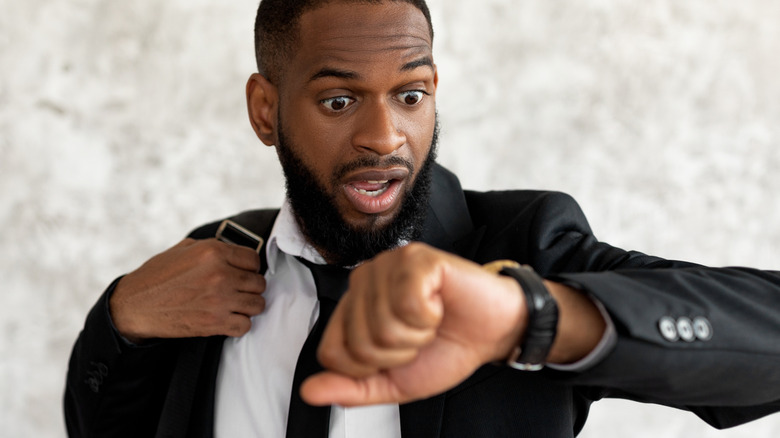 Alarmed-looking man looking at watch