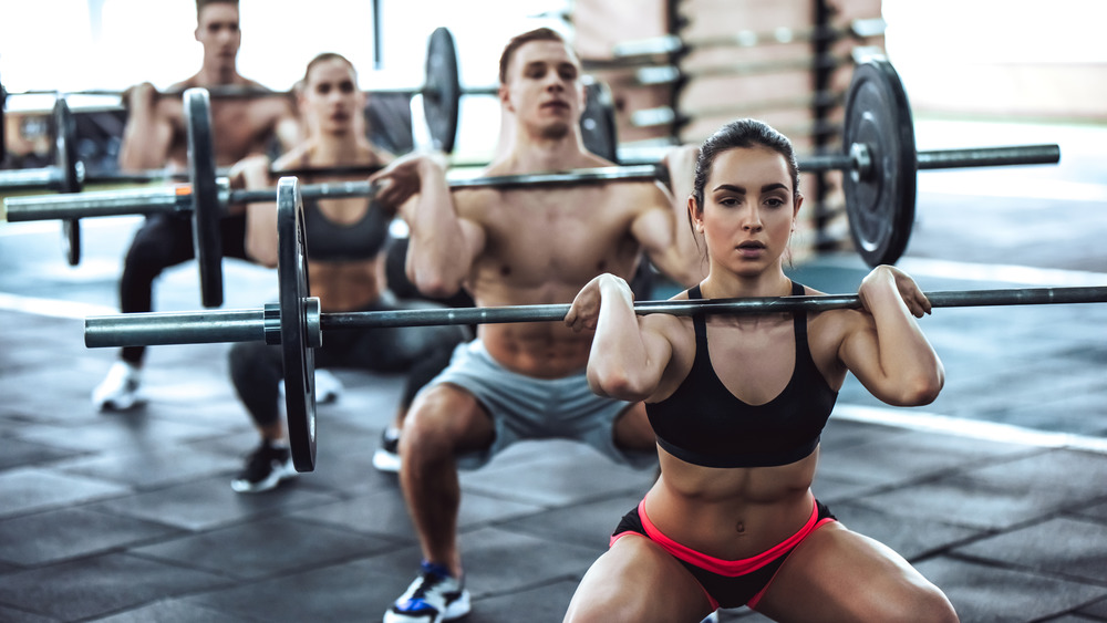 Group of people performing squats with barbells