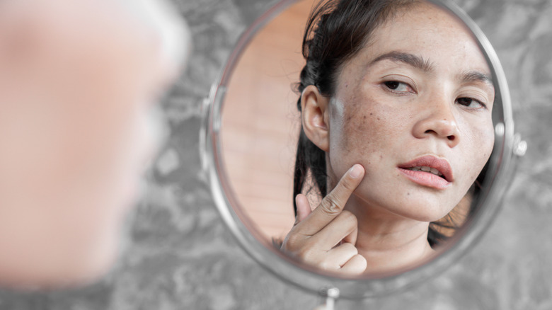 woman looking concerned in the mirror