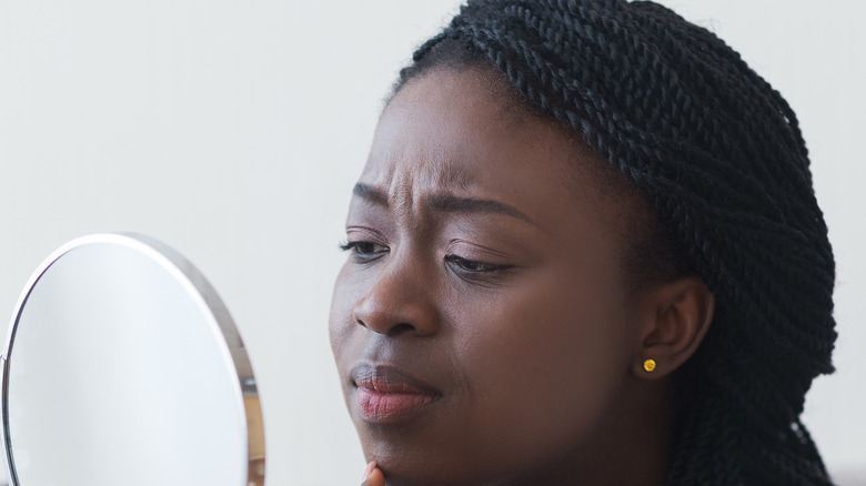 Woman looking at face in mirror