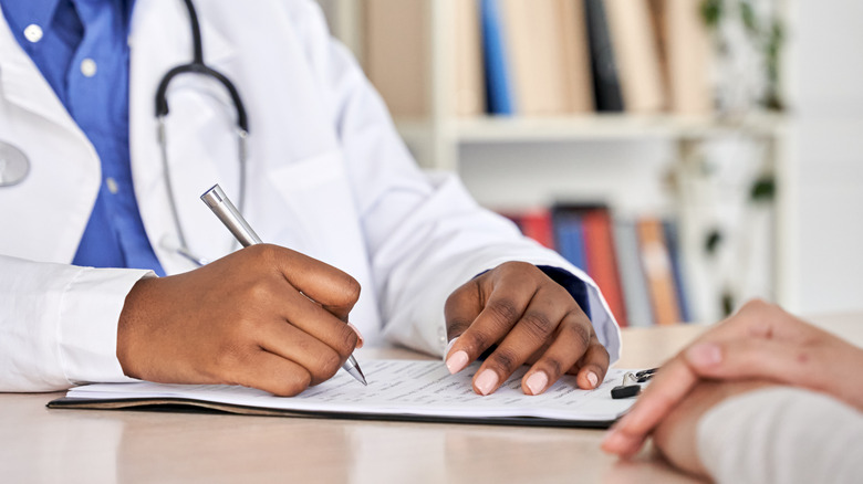 Medical doctor's clipboard and patient's hands