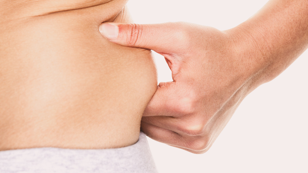 closeup of a woman pinching her love handles 