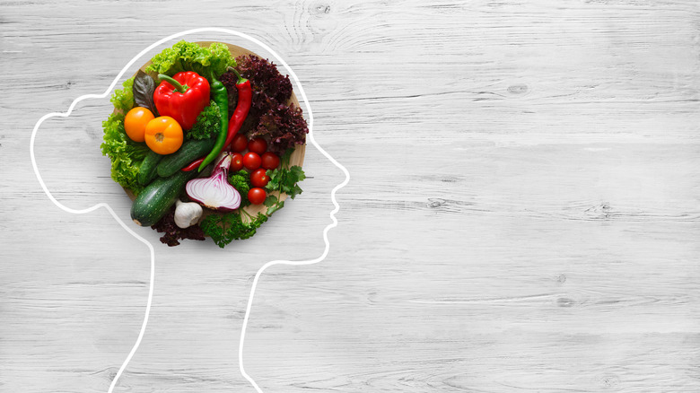 an outline of a head with a plate of vegetables inside
