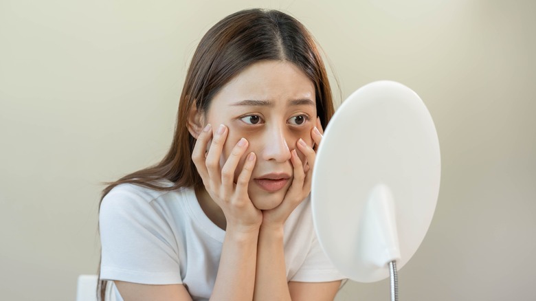 woman staring at face in the mirror