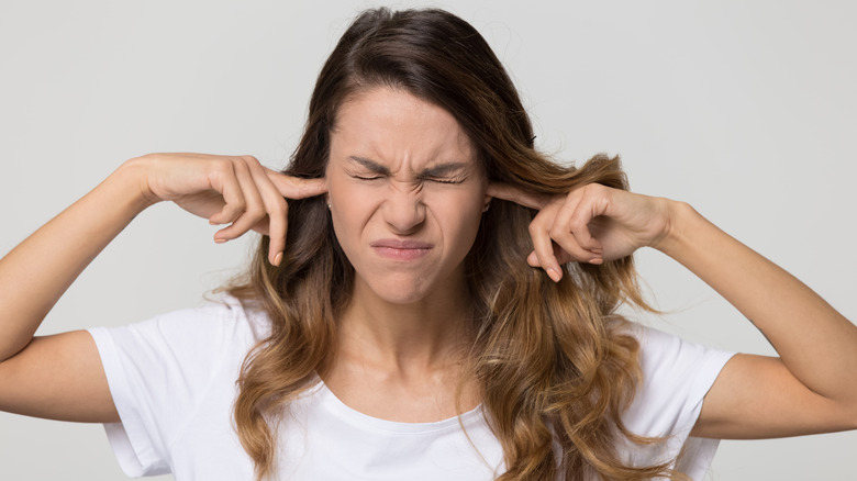 Woman frowning holding her fingers to her ears