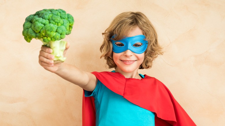 boy with mask holding broccoli