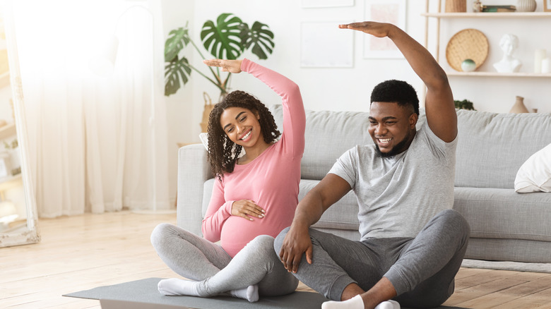 Pregnant woman and man stretching 
