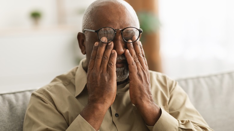 elderly man rubbing his eyes