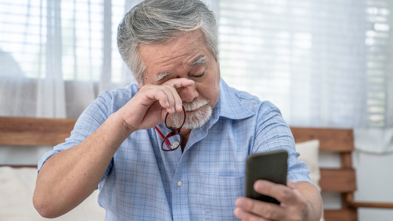 elderly man rubbing eyes