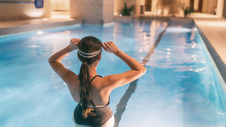 A woman gets ready to swim in a pool