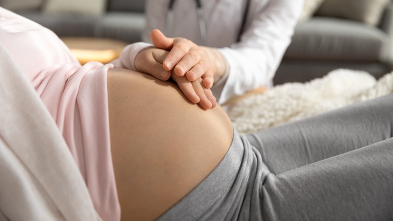 Pregnant woman with doctor's hand on her belly