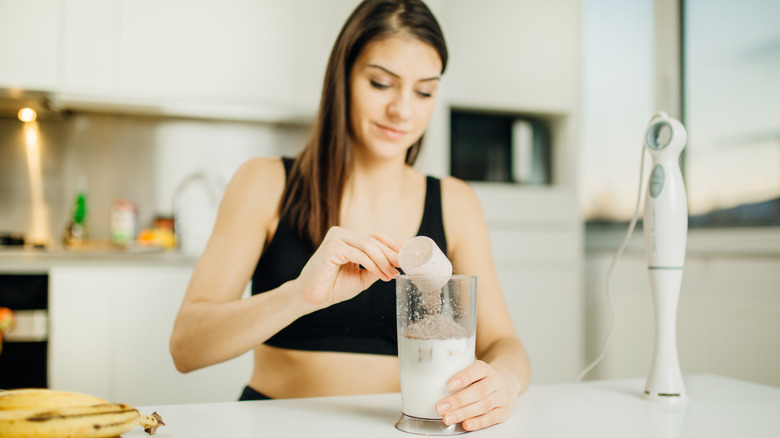 young woman adding protein powder into shaker