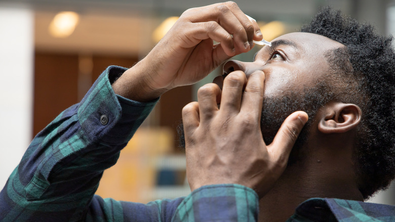 Elderly man with glaucoma putting eyedrops