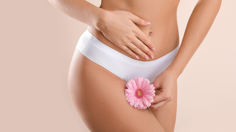 woman holding flower over white underwear