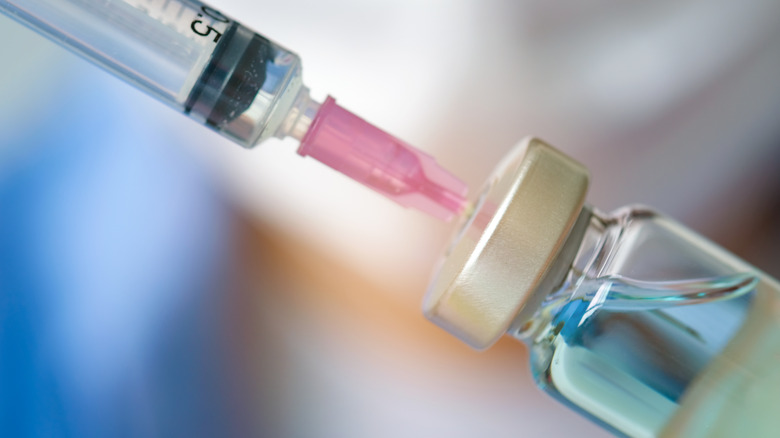 Syringe inserted into blue vaccine bottle