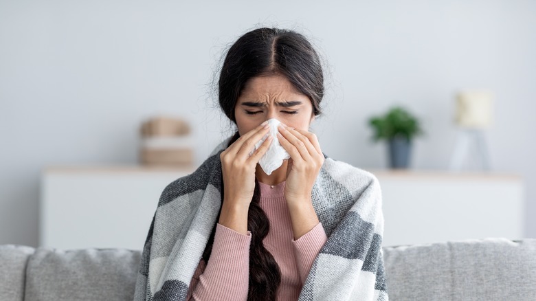 woman on couch blowing nose