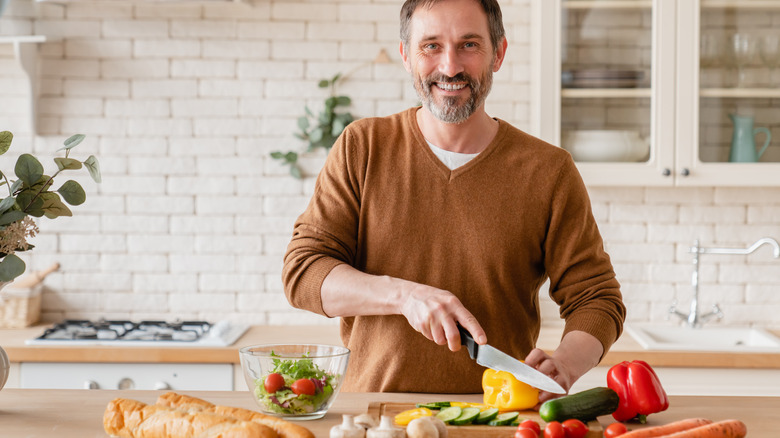 older man cutting up vegetables in the kitchen