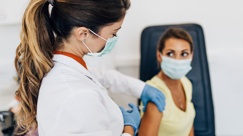 A woman gives another woman a booster shot