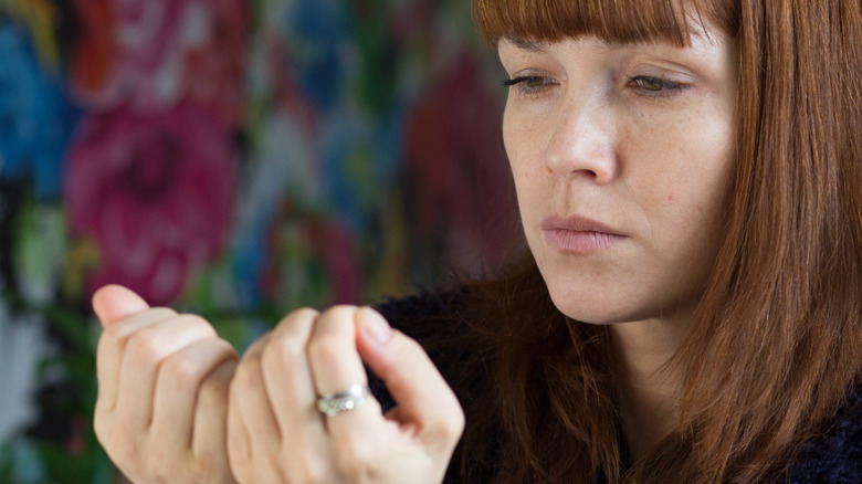 woman looking at fingernails with concern