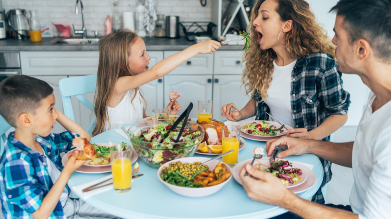 family eating chicken, salad and vegetables
