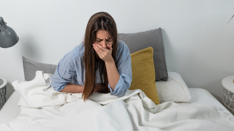 women in bed feeling sick