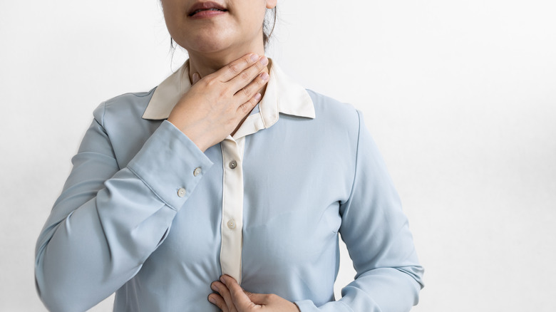 Woman holding throat and stomach