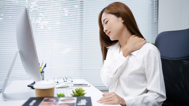 woman at computer and holding her neck