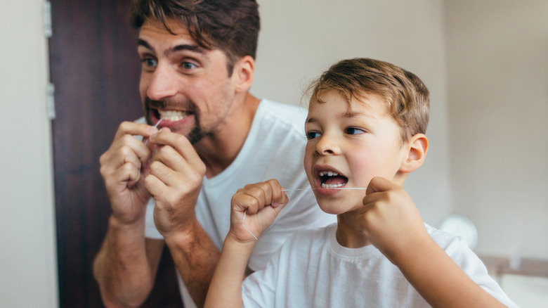 A kid and dad floss teeth