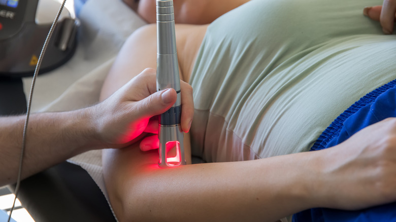 person receiving cold laser therapy on their elbow