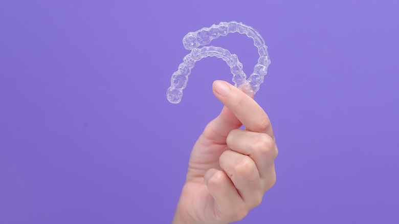 A person holds Invisalign aligners