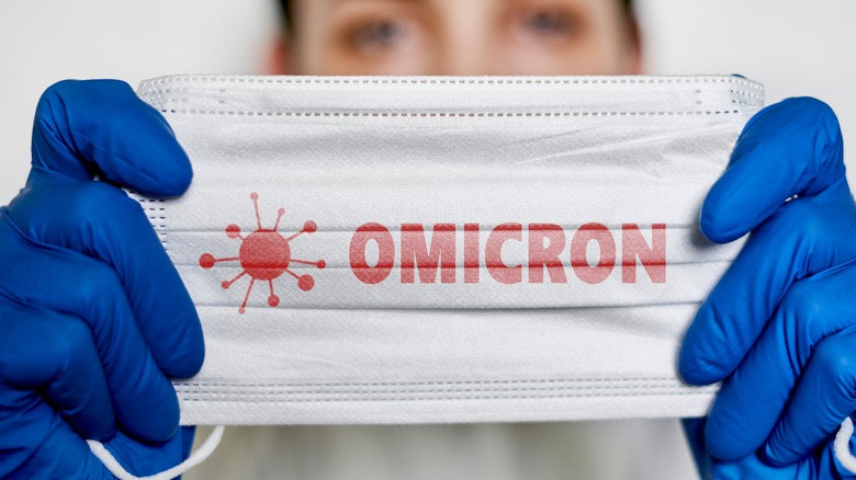 Woman holding a mask that says "Omicron"