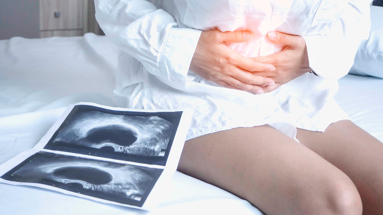 Woman in hospital holding abdomen