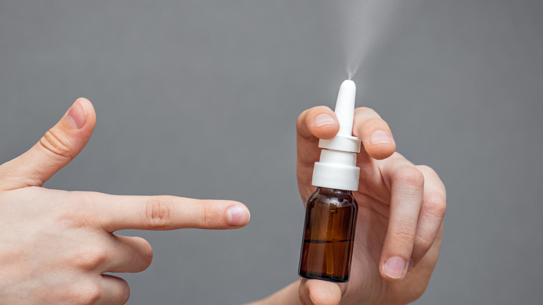 finger pointing toward nasal spray