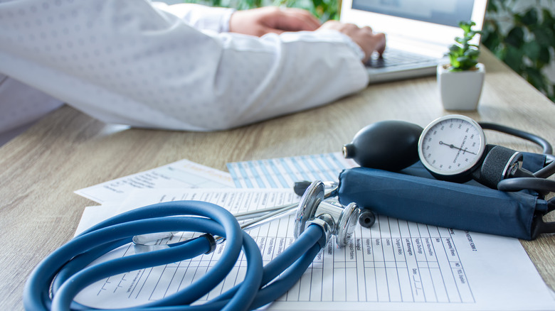 doctor tying with sphygmomanometer on desk