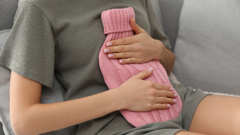 Woman holding hot water bottle on stomach