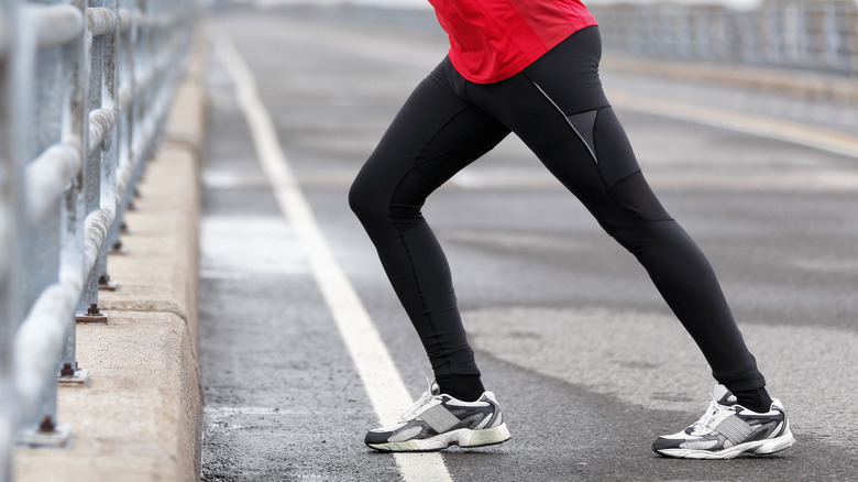 a runner stretching his calves by a railing