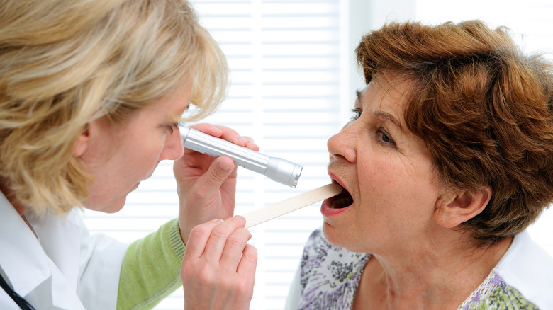 Doctor examining the mouth of a patient with a flashlight