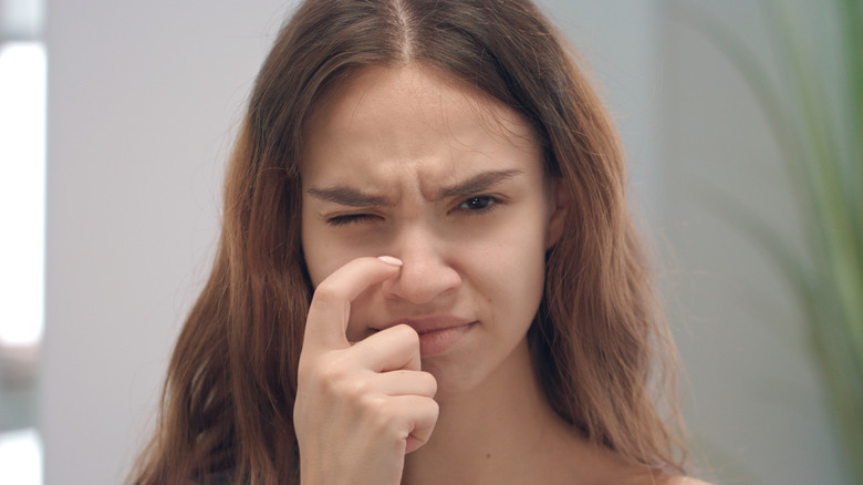 Woman scratching side of her nose