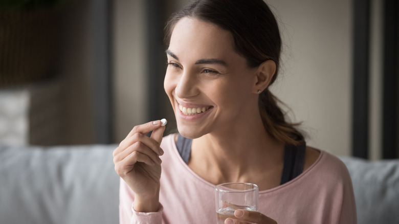 A woman is taking vitamins at home