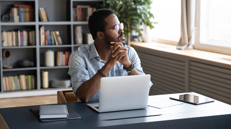 Man looking out window lost in thought