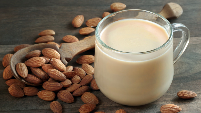 Glass of almond milk with almonds next to it